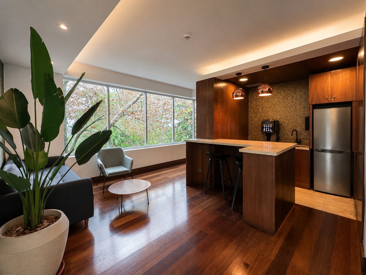 Kitchenette con barra, terminaciones en madera y vista al entorno verde